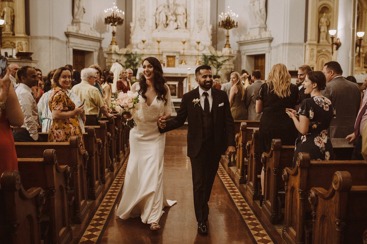 M and Y walking down the aisle as married at their Detroit wedding